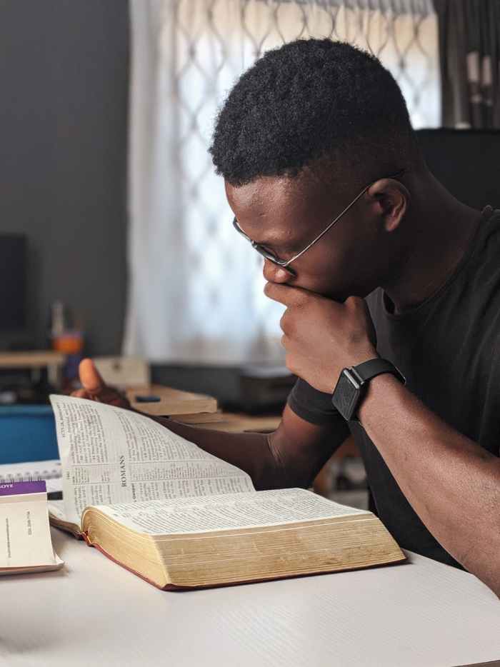 man wearing black crew neck shirt reading book bible study